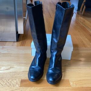 Black leather Italian riding boots with rubber sole .